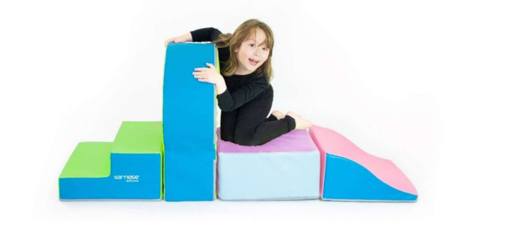 Jeune fille souriante sur un parcours de modules de motricité colorés pour psychomotricité et matériel d’équipement sportif scolaire.